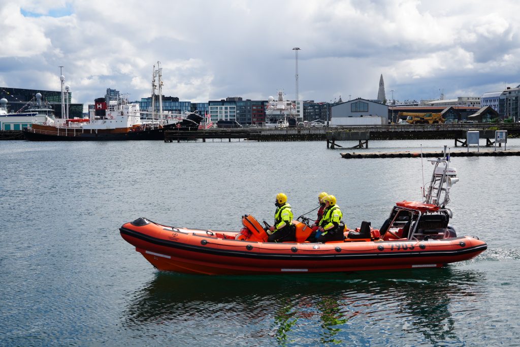 Three Search and Rescue members sail on a rescue boat. 