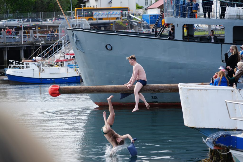 A competitor falls into the water during a pillow fight.  