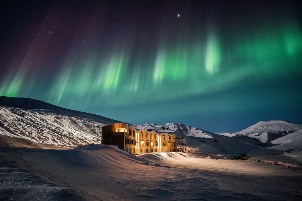 Event planning in a snowy mountain lodge beneath vibrant green Northern Lights