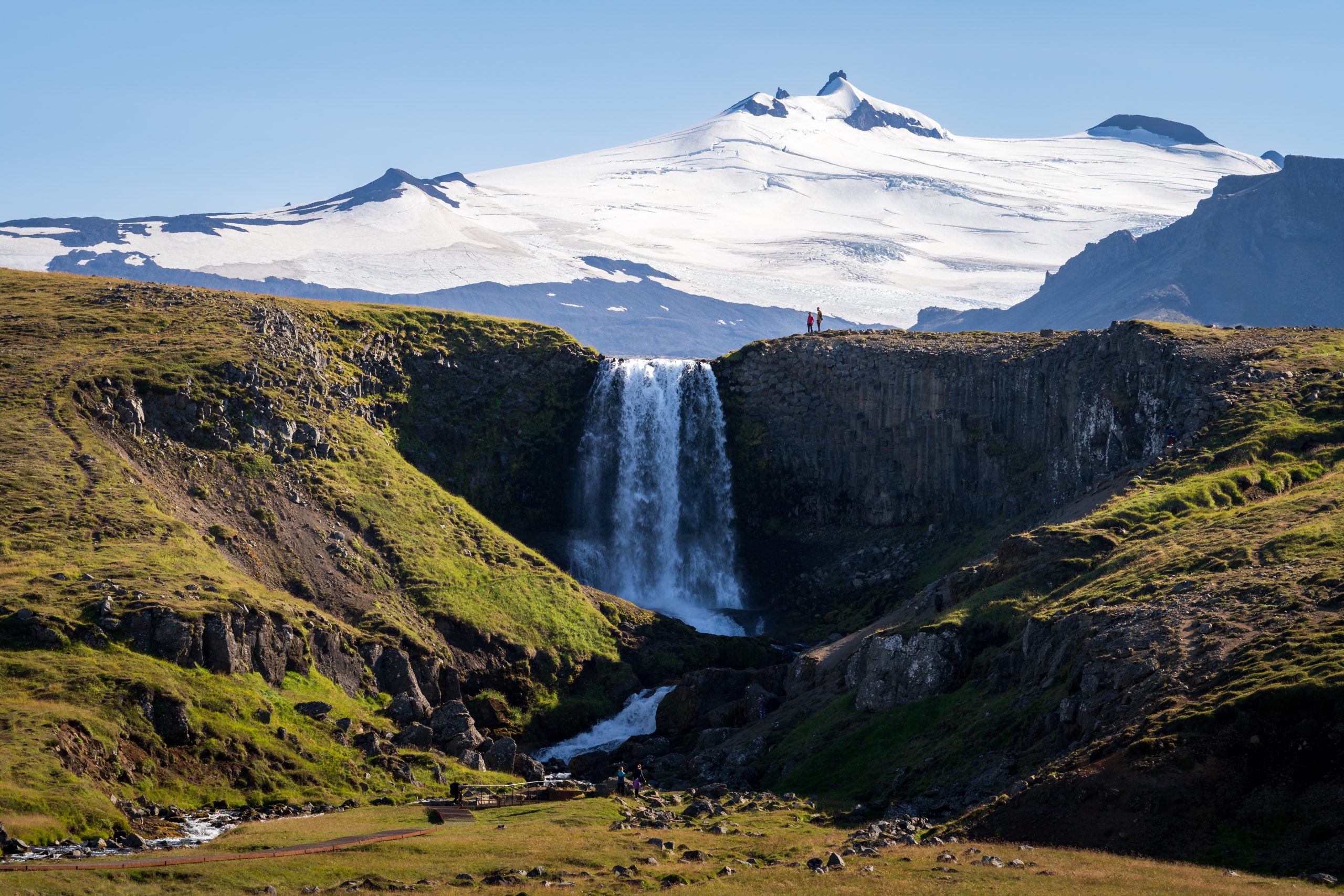 Event planning in Iceland surrounded by a dramatic waterfall, glacier and mountain landscape